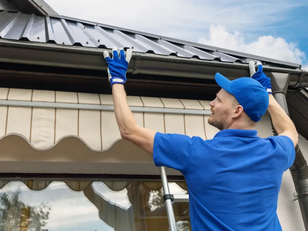 a man wearing blue uniform and gloves holding up a roof while installing a commercial roof system